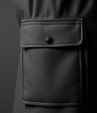 Dettaglio tasche geometriche su cappotto antracite